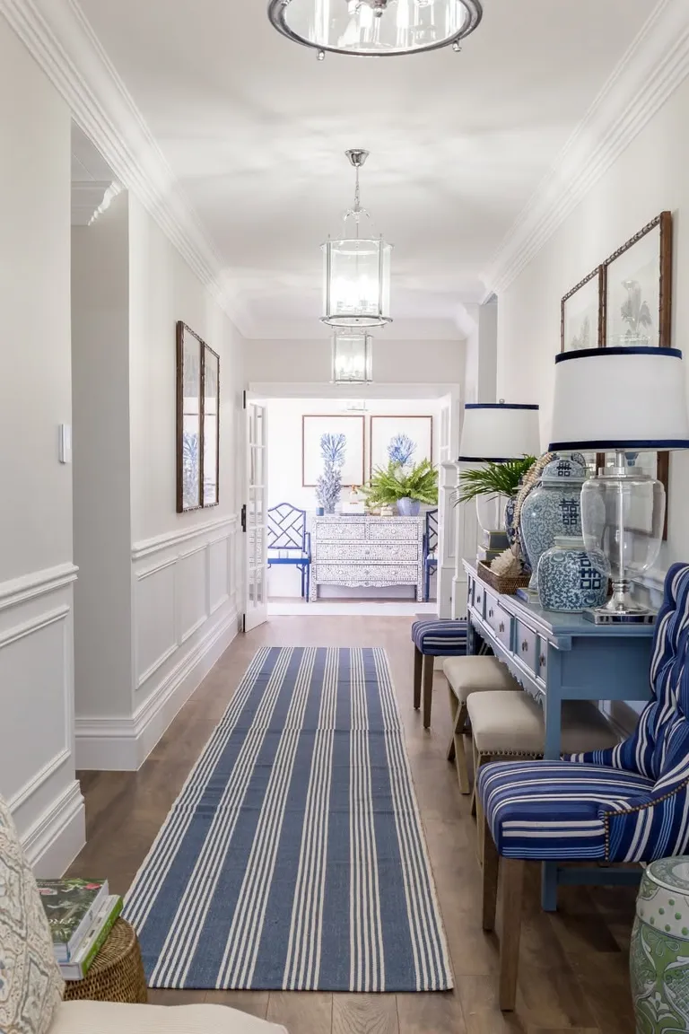 Traditional hallway with white raised panel wainscoting and a blue striped runner