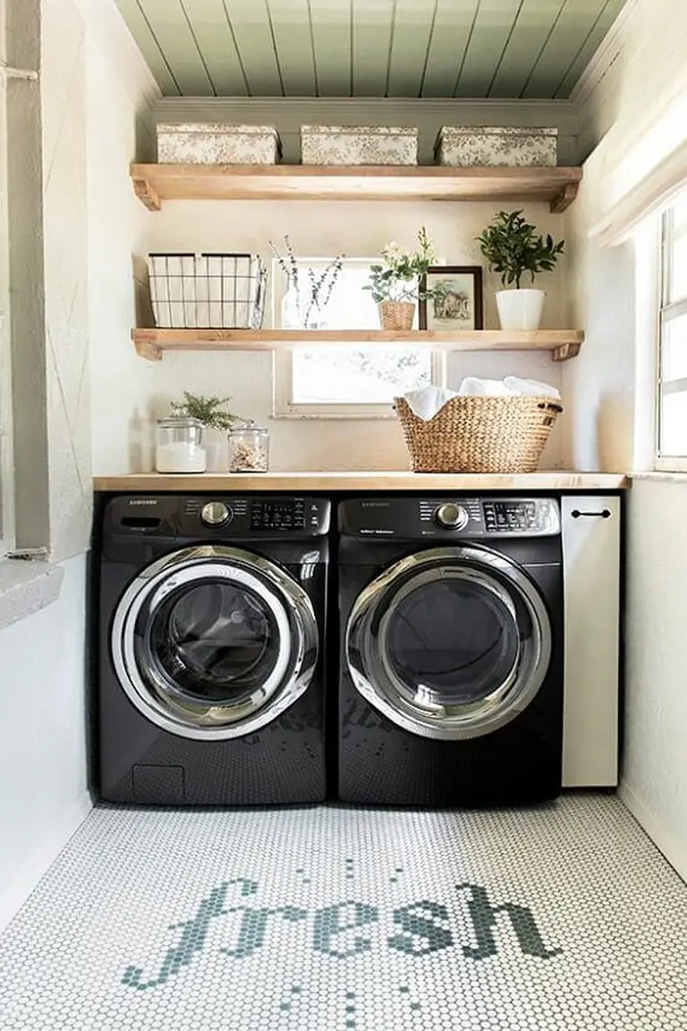 Small laundry room with two oak shelves above white machines holding labeled baskets and detergent bottles