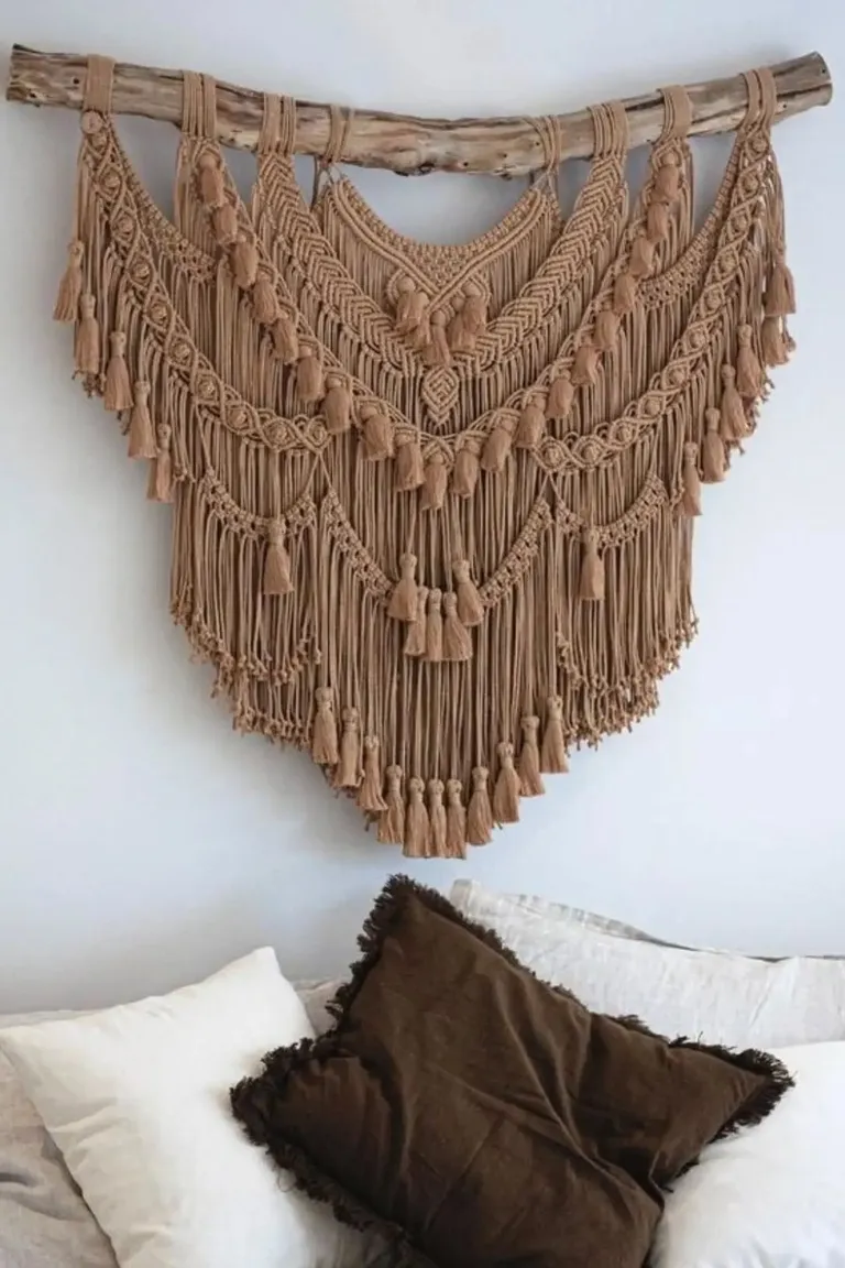 20 Renter-Friendly Bedroom Ideas for a Cozy Space Without Painting 3 Fabric wall hanging with tassels on a white wall above a bed with neutral linen bedding in a rental bedroom