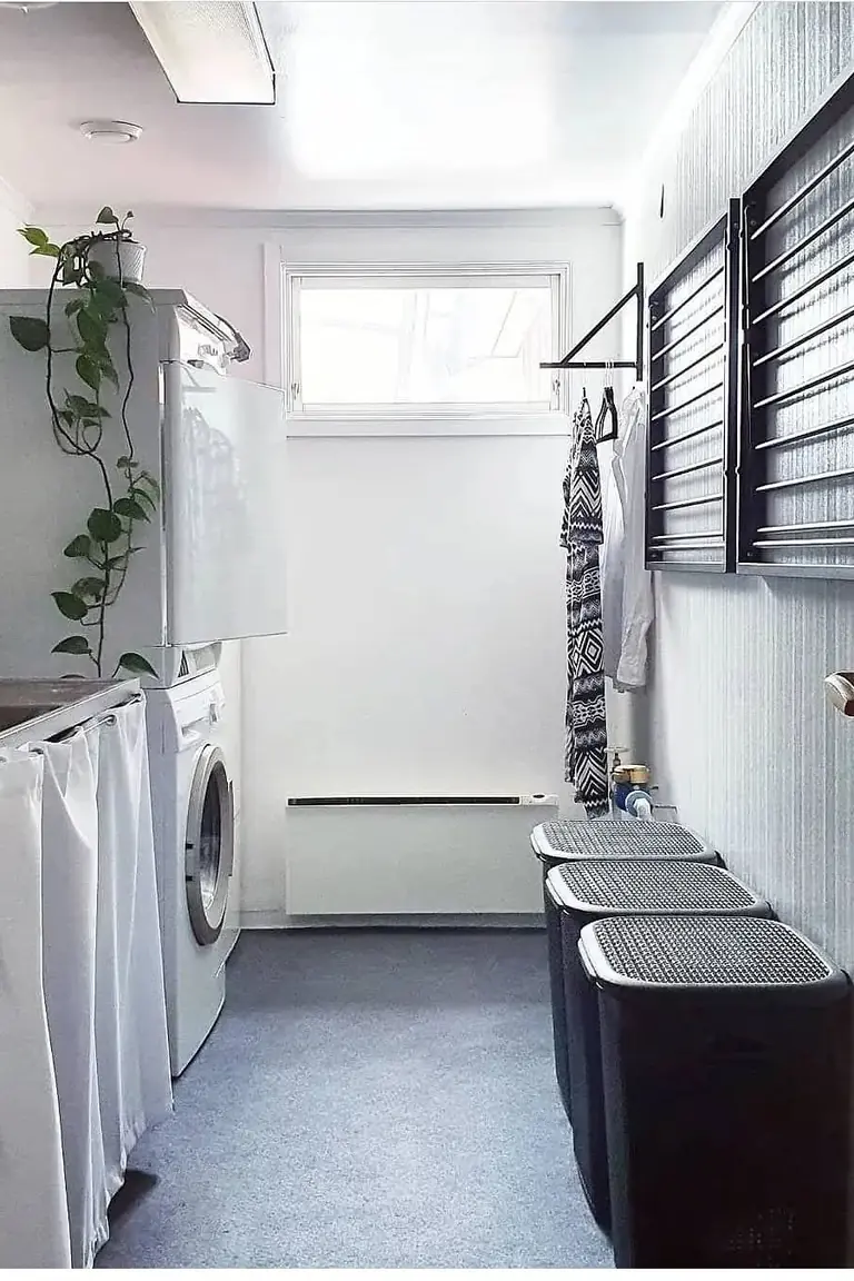 Wall mounted folding drying rack with shirts and delicates in a bright laundry room