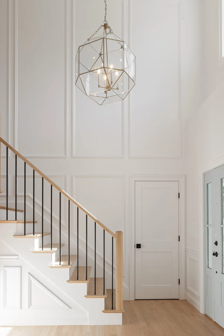 Formal foyer with full height white paneling, a geometric chandelier and a staircase
