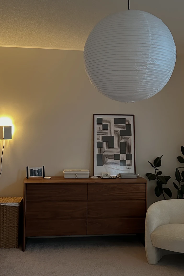 20 Renter-Friendly Bedroom Ideas for a Cozy Space Without Painting 5 Oversized framed art leaning against the wall on a wooden dresser in a renter friendly bedroom