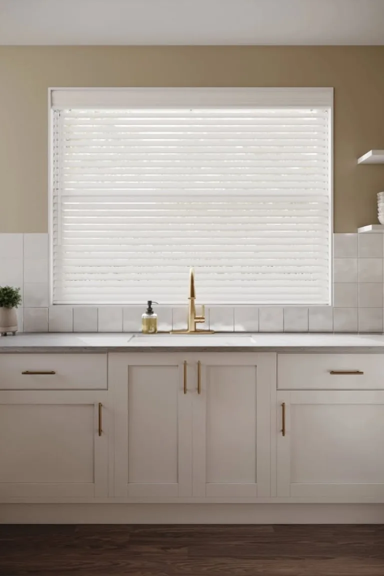 Bright kitchen with white horizontal blinds over the full sink window, plant on the counter and white shaker cabinets