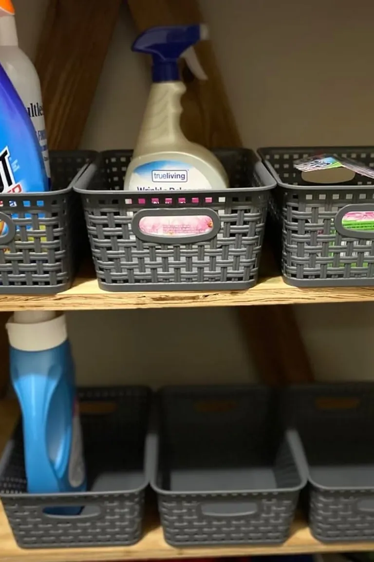 Two rows of matching baskets with label slots holding laundry supplies on wooden shelves