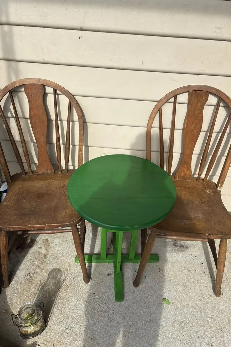 Small patio with two vintage wooden chairs and a bright green repainted round table
