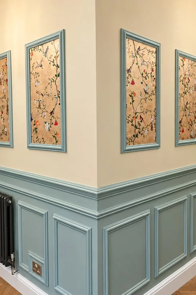 Hallway corner with dusty blue panel molding, cream upper walls and framed artwork