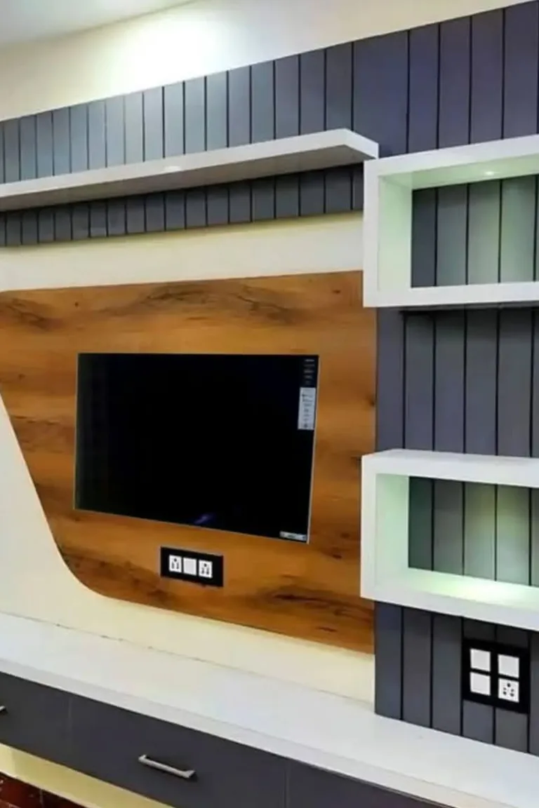 A living room TV wall with white floating shelves arranged asymmetrically around a wall mounted television above a long low console.