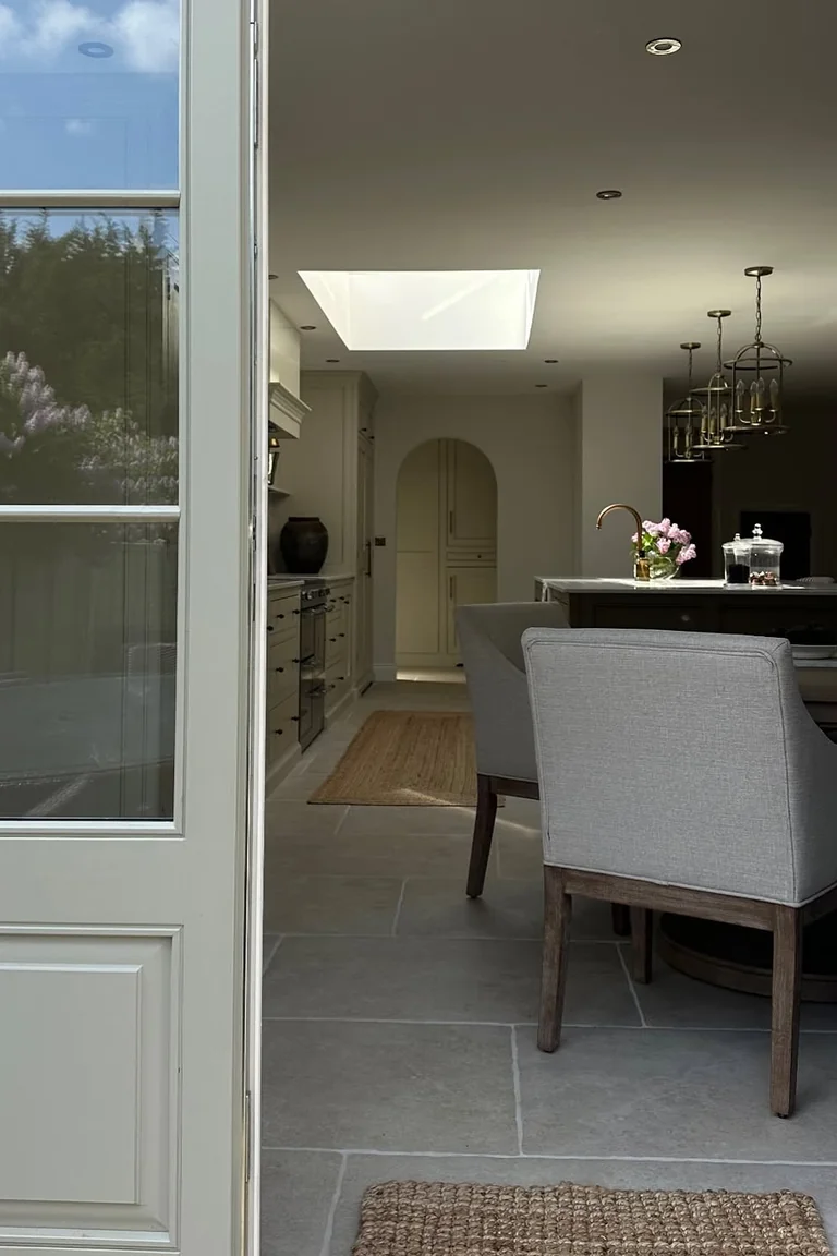 18 Small Kitchen Partition Ideas 16 White French door with glass panes opening into a kitchen and dining area with grey chairs