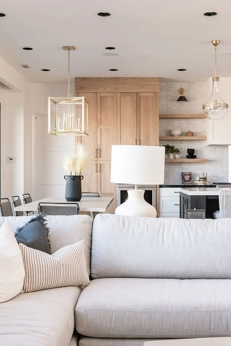 18 Small Kitchen Partition Ideas 17 Light grey sectional sofa with two white lamps behind it, kitchen and dining area beyond