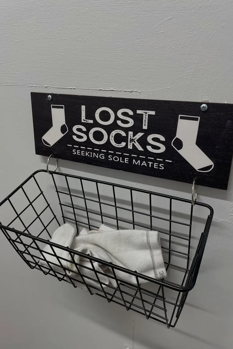 Wall mounted wire basket holding single socks under a lost socks sign