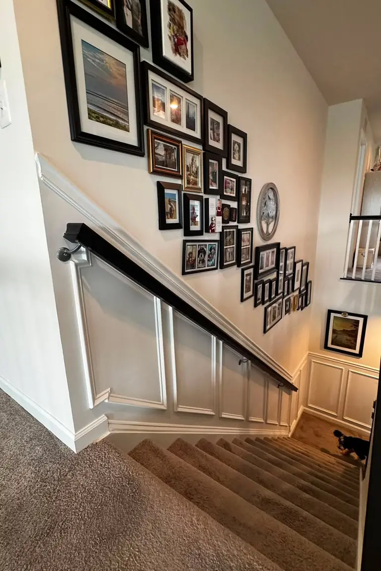 Carpeted stair hallway with white wainscoting following the slope and a gallery wall above