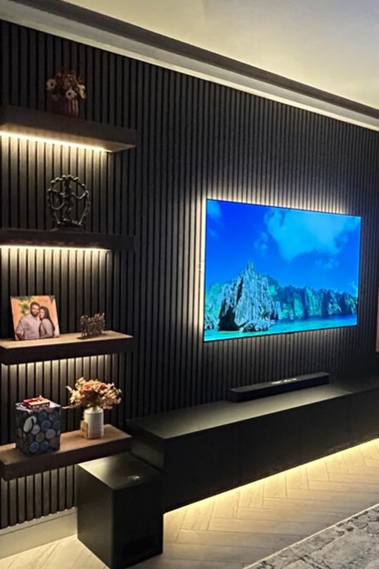 25 Stunning Accent Wall Ideas for Every Room and Style 20 Living room with a charcoal slat media accent wall, floating oak shelves holding decor, a TV, a rug and a cabinet
