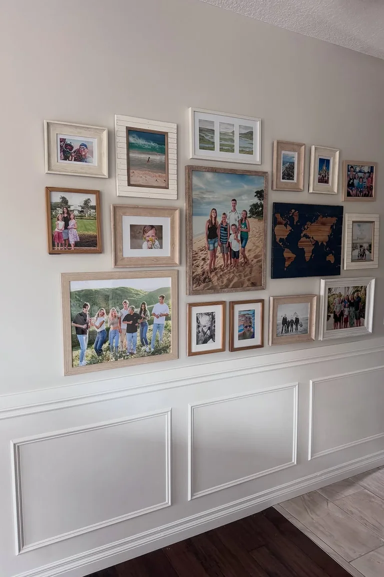 Hallway wall with white picture-frame wainscoting and a gallery wall of framed family photos above
