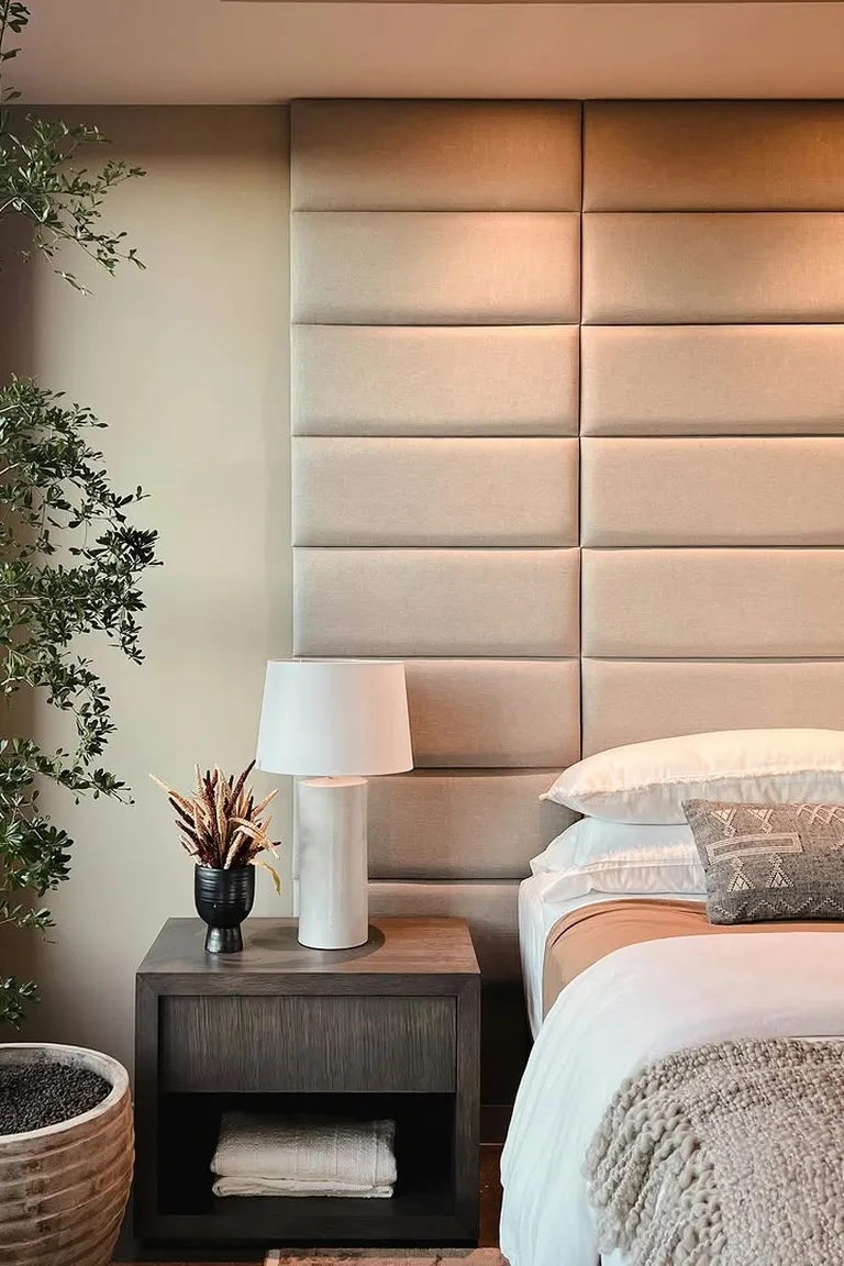 25 Stunning Accent Wall Ideas for Every Room and Style 22 Bedroom with a floor-to-ceiling upholstered fabric panel wall behind a bed, a nightstand, a lamp, a plant and a window