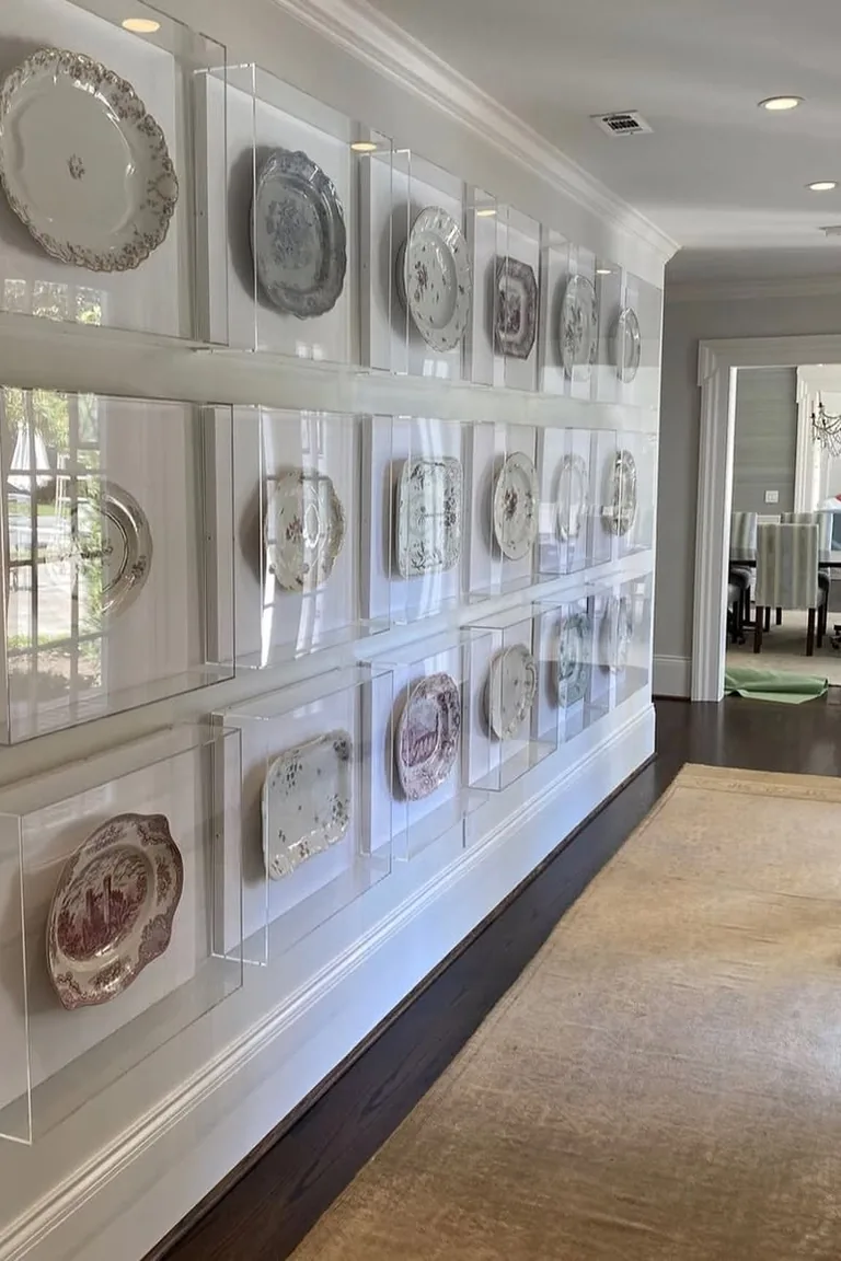 Hallway with decorative plates displayed in shadow boxes above white wainscoting