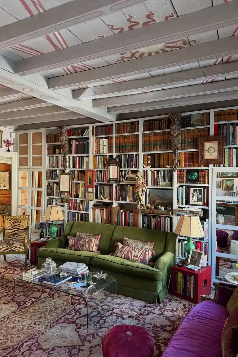 25 Stunning Accent Wall Ideas for Every Room and Style 26 Living room with a floor-to-ceiling white bookshelf wall, a green sofa facing the shelves, plants, artwork and warm lighting