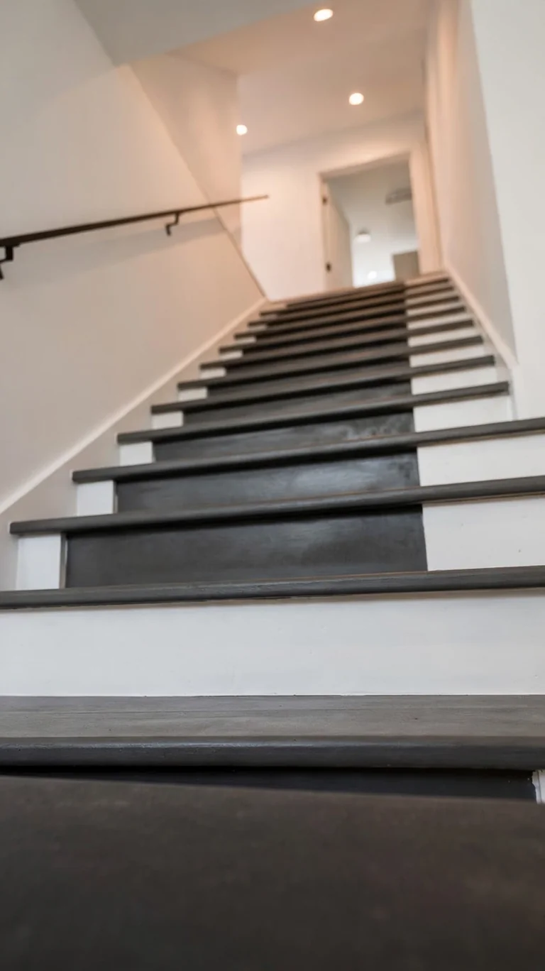 Basement stairs painted in two tones with dark treads and white risers.