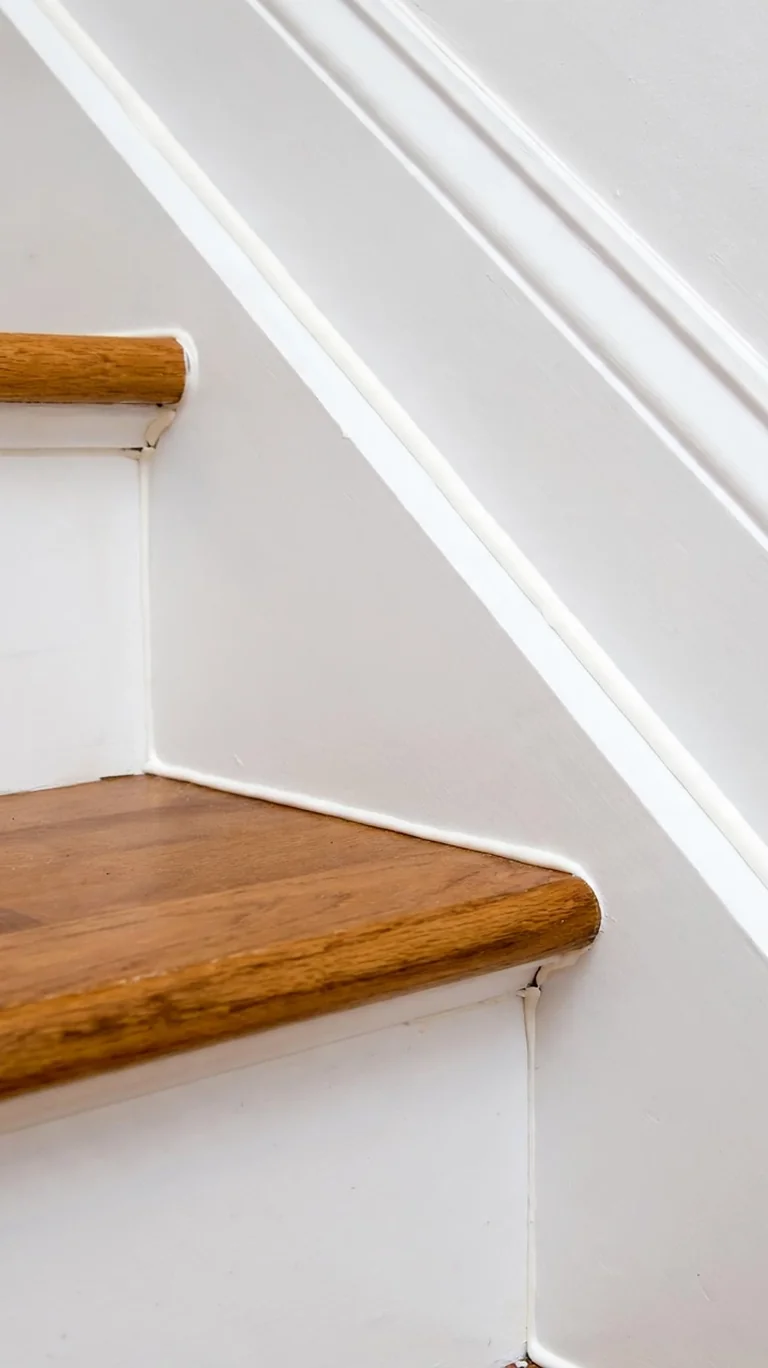 Basement stairs finished with crisp white trim and baseboards along the stringer.