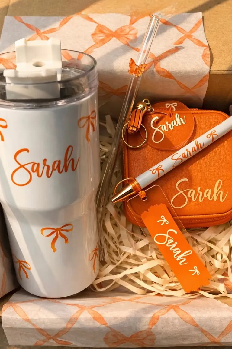 Personalized gift set with a named tumbler, pouch, keychain, pen, and tag in matching orange and white.