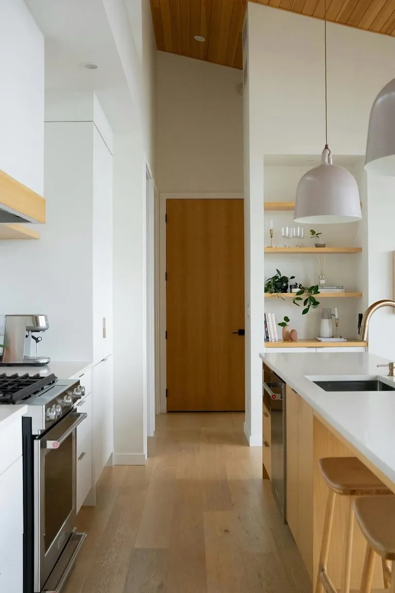Bright U-shaped kitchen with white cabinets, oak accents, and three runs of countertops